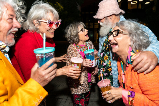 Group of happy senior friends with fancy clothing having party in the night