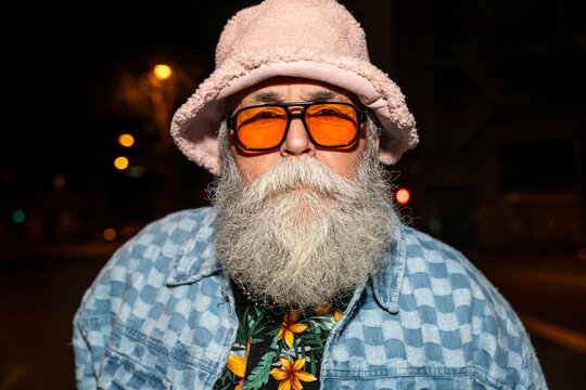 Senior bearded man with fancy clothing having party in the night on city streets