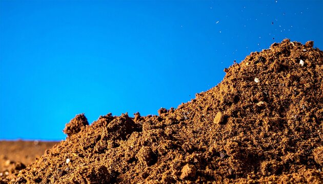 Coarse pile of brown earth with small stones and fragments presented  isolated on blue background
3
