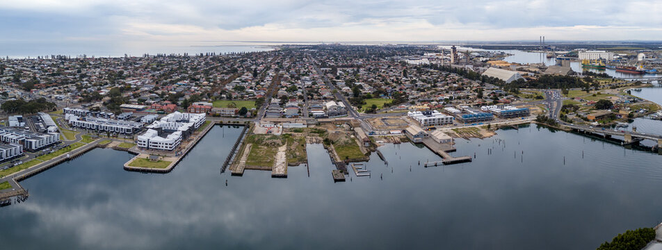 Panoramic aerial drone view of Port Adelaide and the Port River waterfront, with new housing developments, historical harbor basins, industrial shipping areas, and suburban street in South Australia