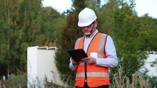 Energy engineer using AI algorithms on digital tablet to optimise and check data, controlling project energy and site work. Sustainable power generation, efficiency, smart grid.