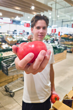 Young Shopper Holding Fresh Red Tomato in Supermarket
