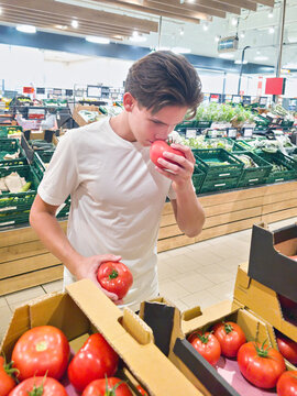 Young Shopper Smelling Fresh Red Tomato in Supermarket