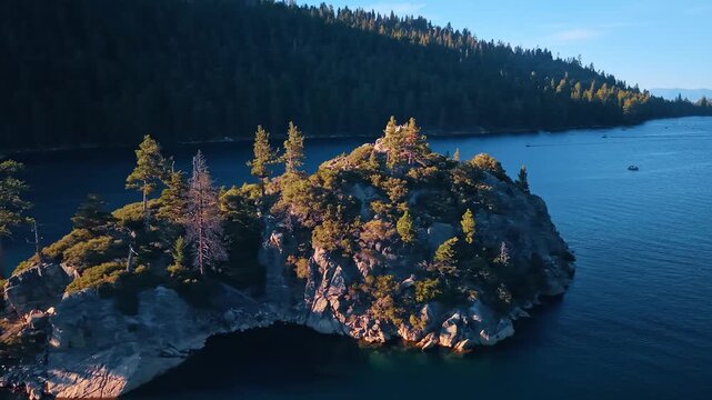Wooded cliffs of Fannette Island above Emerald Bay. Trees and shrubs cover a granite island, with a small ruin on the summit and forest beyond the water.