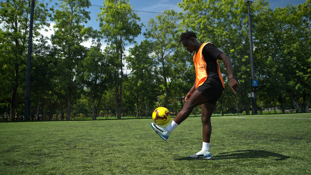 Soccer player tracking and controlling the ball during an outdoor training session, highlighting focus,