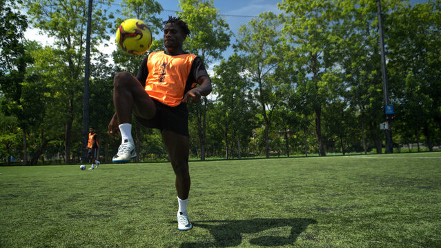 Soccer player tracking and controlling the ball during an outdoor training session, highlighting focus,