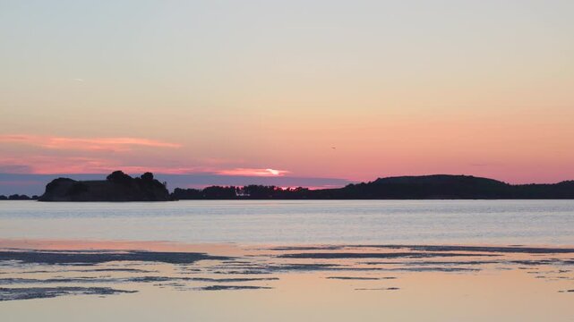 Serene Sunset Over Calm Ocean Water With Distant Island Silhouettes And Soft Pink Sky Colors During Peaceful Dusk. Seaside landscape near the city of Vlore in Albania, Europe.