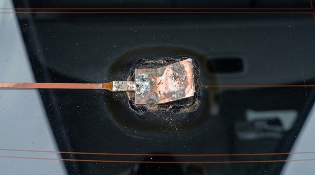 Close up of a damaged car rear window defroster heating element connector