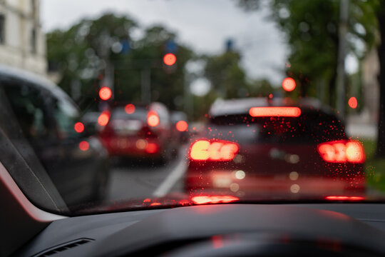 Rainy traffic queue viewed through a car windshield with glowing brake lights, supporting urban congestion analysis, commuter transport planning, and roadway operations