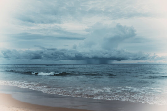 Dramatic storm clouds and rain over the sea with ocean waves on a moody overcast day