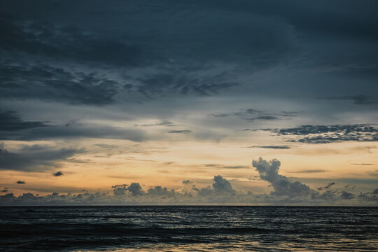 Dramatic sunset over the sea with heavy dark clouds and golden light on the horizon