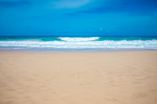 Tropical paradise beach with golden sand and turquoise ocean waves under blue sky, summer holiday background