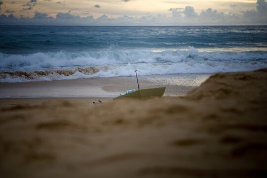 Lost umbrella on the sand with powerful ocean waves at sunset, conceptual beach landscape