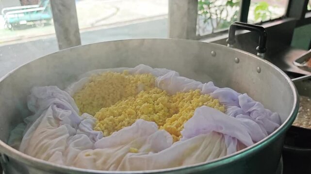 Steaming yellow split mung beans with cheesecloth in a metal steamer.
