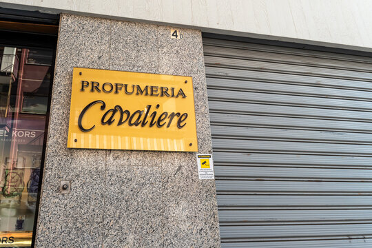 Barletta, Italy - Aug 1, 2026: Gold plaque of Profumeria Cavaliere with black lettering fixed to a granite column beside a closed metal roller shutter on a shopping street