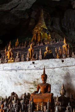 Golden Buddha statues and a stupa fill the Pak Ou Caves in Luang Prabang, Laos, creating a sacred religious site carved into limestone.