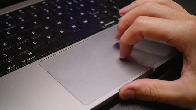 A man is typing moving his finger on a laptop trackpad at work in a business environment 