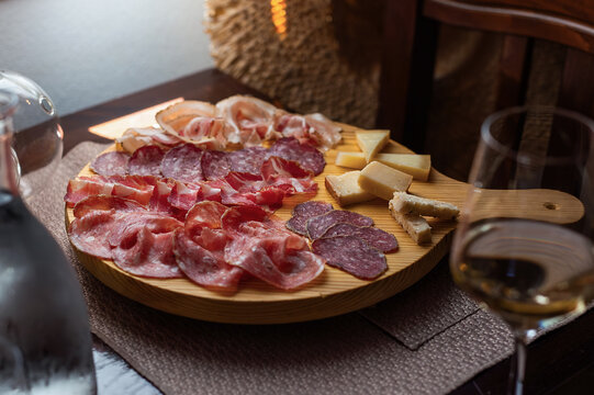Board of cured meats and cheese with a glass of white wine in an elegant interior