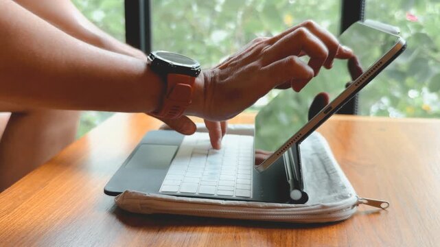 Hands typing on a modern tablet with a keyboard case. Remote work and digital productivity.
