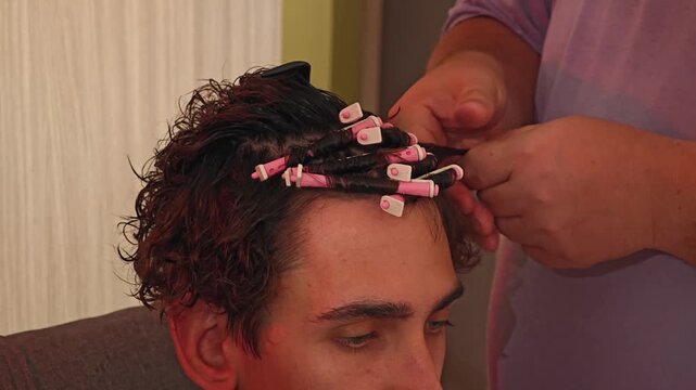 Hairdresser winding perm rods. man is getting her hair done by a stylist.