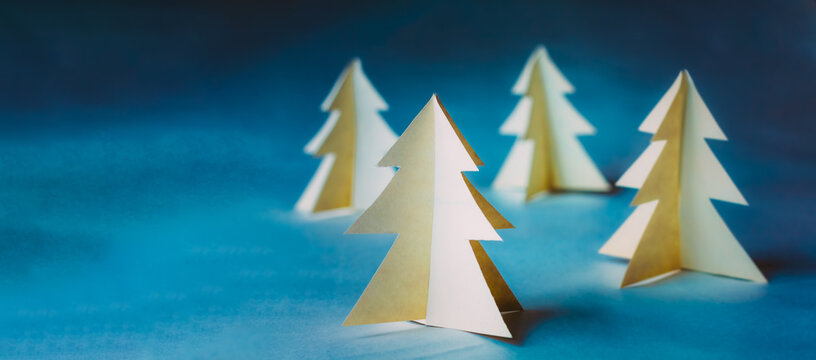White paper origami Christmas trees on a blue background