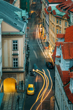 Motion light trails on a curved Prague alley at dusk