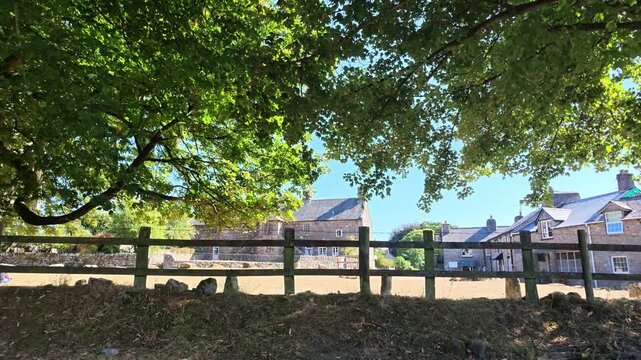 Widecombe in the Moor Devon England UK. 20.08.2026. Video. View of village green during a hot summer resulting in dried grass. shot from shadow of a large tree.