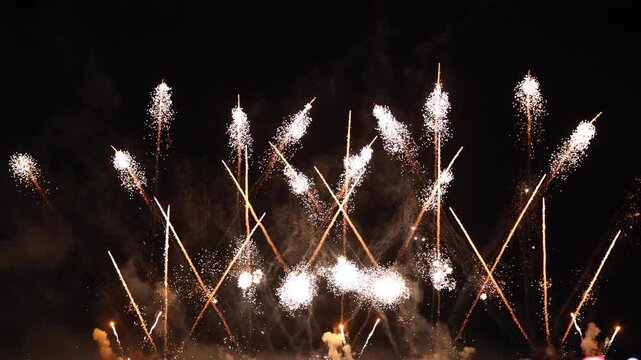 Spectacular fireworks display bursting in night sky with golden sparks and laser light rays over dark background, bright pyrotechnics celebration, holiday show, party, and festival concept