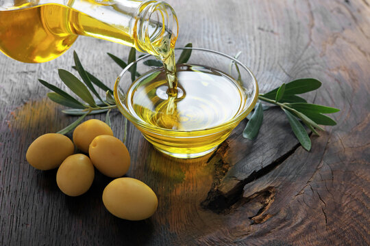 Organic olive oil pouring from a glass carafe into a glass bowl