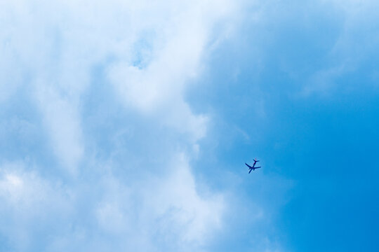 commercial passenger airplane flying under blue sky viewed from below