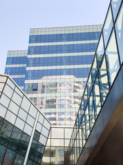 Obraz premium Building reflections in a modern urban setting with glass architecture and clear sky