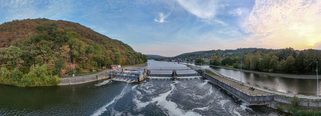 Obraz premium vue aérienne panoramique du barrage d'Hermetton dans la commune d'Hastière (province de Namur), en Belgique. les remous de l'eau de la Meuse en fin d'après midi