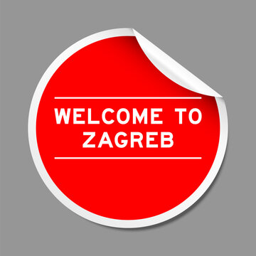 Red color peel sticker label with word welcome to zagreb on gray background