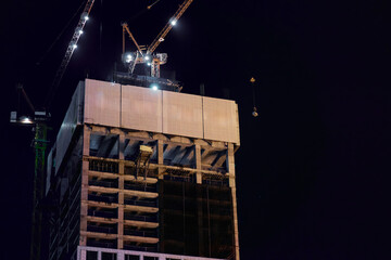 Nighttime High-Rise Construction Site With Illuminated Tower Cranes Over Concrete Skeleton © Loginova