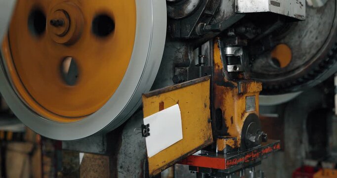 Close up of spinning flywheel and belt of industrial metal stamping press machine in factory
