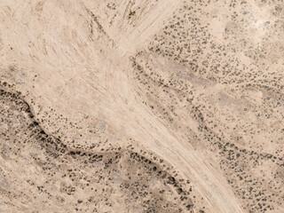 Obraz premium aerial view of winding dirt road through desert shrubs