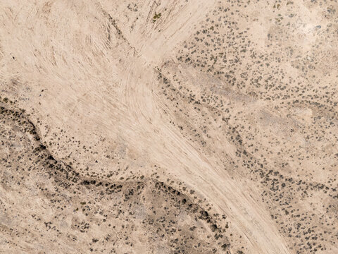 aerial view of winding dirt road through desert shrubs
