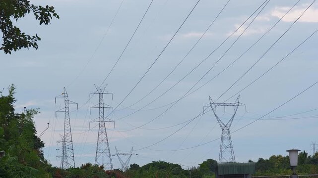 High voltage electricity transmission towers standing on a mountain ridge, surrounded by a natural landscape under daylight.	