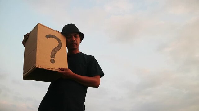 Man holding a cardboard box with a question mark, symbolizing mystery and uncertainty.