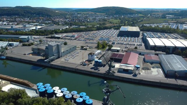 Drone aerial approaching Kelheim Port and a large car terminal with thousands of vehicles, industrial facilities and cargo infrastructure along the Danube in Bavaria, Germany (2026)