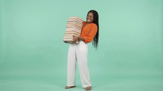 Woman struggles to hold heavy stack of books