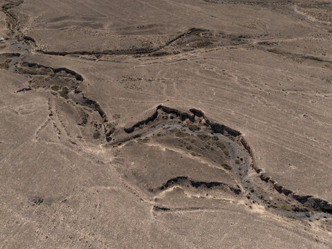 Aerial view of eroded gullies and dry cracked earth in barren desert landscape