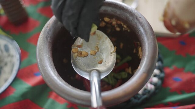 Spoon over a clay mortar as lime is squeezed in for som tam