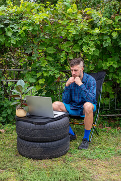 Man Working Outdoors on Laptop at Makeshift Tire Desk
