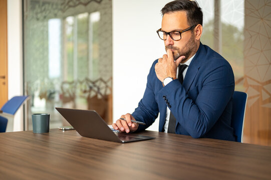 Professional businessman deeply concentrating while working on a laptop in a modern office, planning strategies, analyzing data, or reviewing legal documents