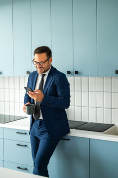 Smiling businessman holding a cup of coffee and checking a smartphone, staying connected and managing professional tasks in a contemporary environment
