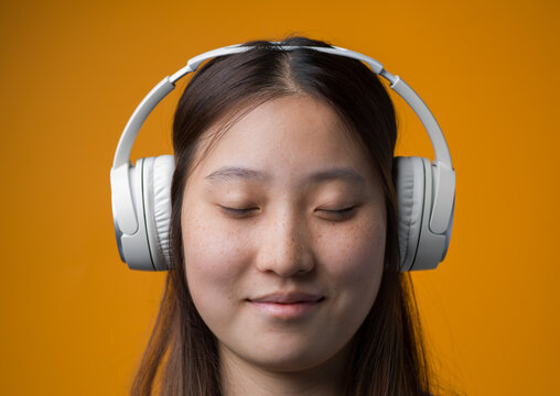 Peaceful Young Chinese Woman Listening to Music with Headphones
