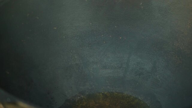 Close-up of large cauldron for pilaf with boiling oil