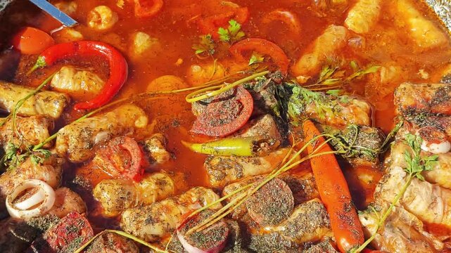 traditional Romanian cabbage rolls - sarmale simmering in a rich, red tomato and pepper sauce garnished with fresh herbs and chili peppers