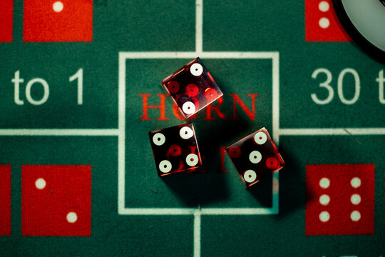 Red casino dice directly inside the Horn bet proposition box on green craps layout. Commercial photo for game nights, betting tournaments, and casino entertainment.